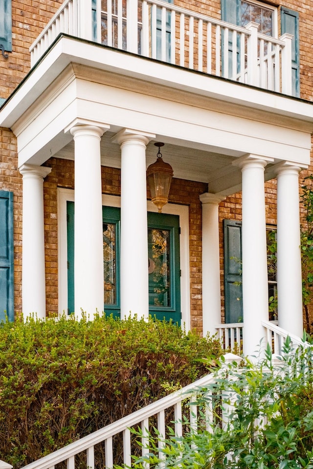 view of exterior entry with a balcony and covered porch