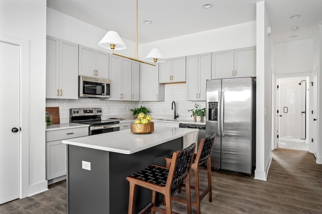 kitchen featuring pendant lighting, dark hardwood / wood-style flooring, stainless steel appliances, and a center island