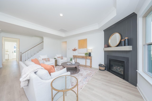 living room featuring a large fireplace, light hardwood / wood-style floors, and ornamental molding