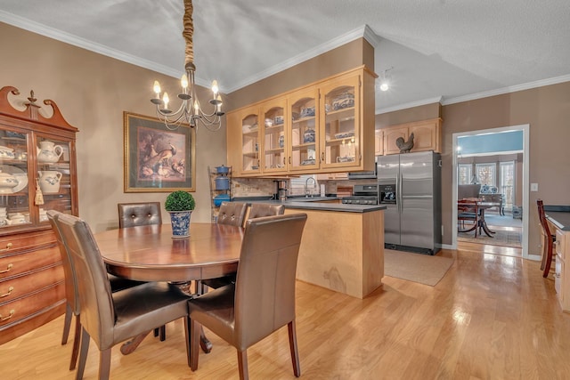 dining area featuring sink, a notable chandelier, crown molding, light hardwood / wood-style floors, and a textured ceiling