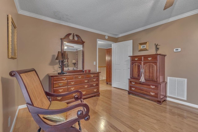 sitting room featuring a textured ceiling, light hardwood / wood-style flooring, and crown molding