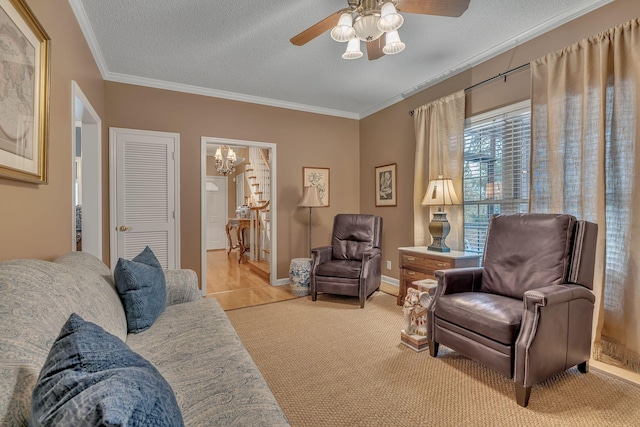 living room featuring ceiling fan, ornamental molding, a textured ceiling, and light carpet