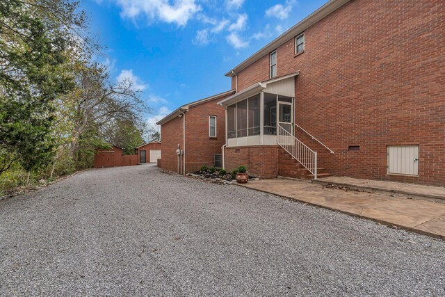 view of home's exterior featuring a sunroom, a patio area, a garage, and an outdoor structure