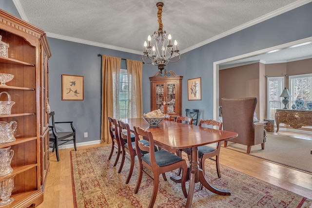 dining space featuring a healthy amount of sunlight, crown molding, light hardwood / wood-style floors, and a textured ceiling