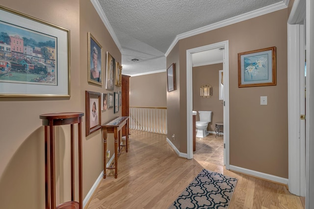 hallway featuring crown molding, light hardwood / wood-style flooring, and a textured ceiling