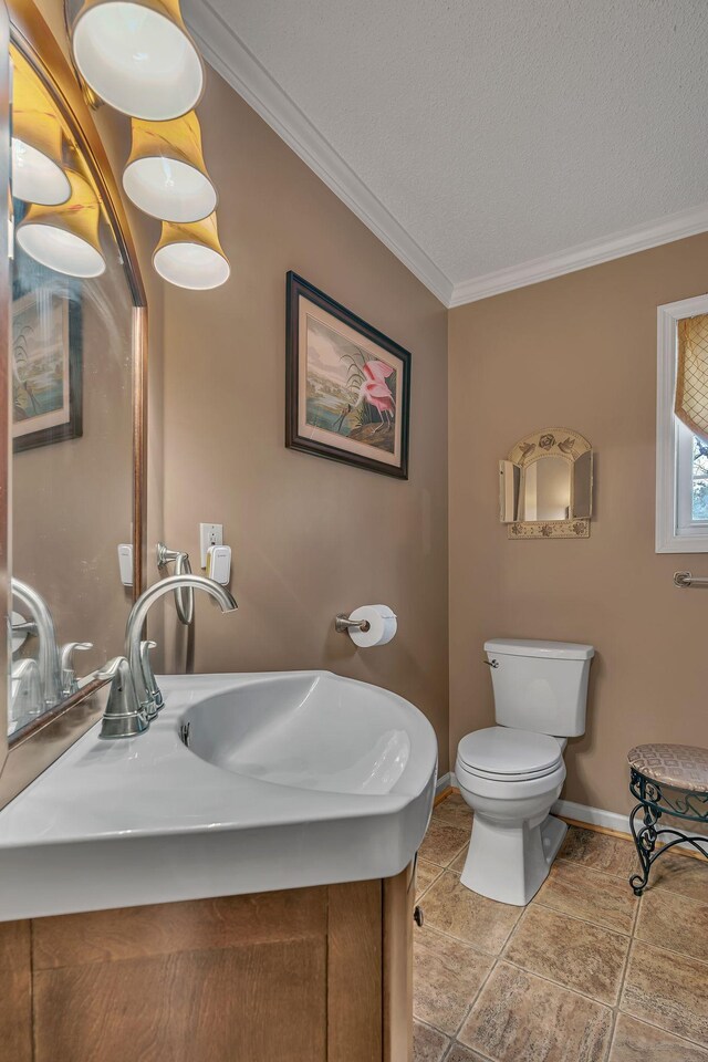 bathroom with a textured ceiling, toilet, sink, and crown molding