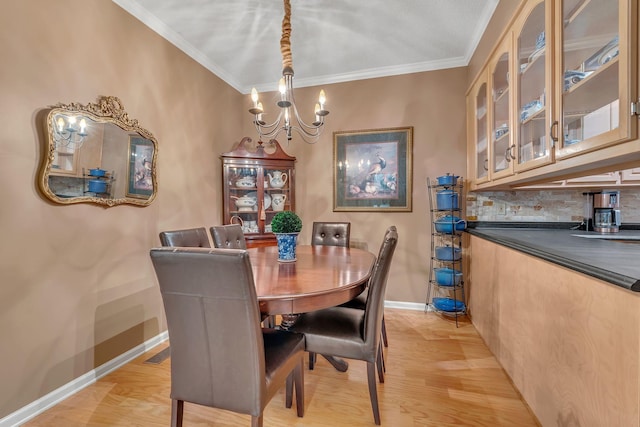 dining space with light wood-type flooring, crown molding, and a notable chandelier