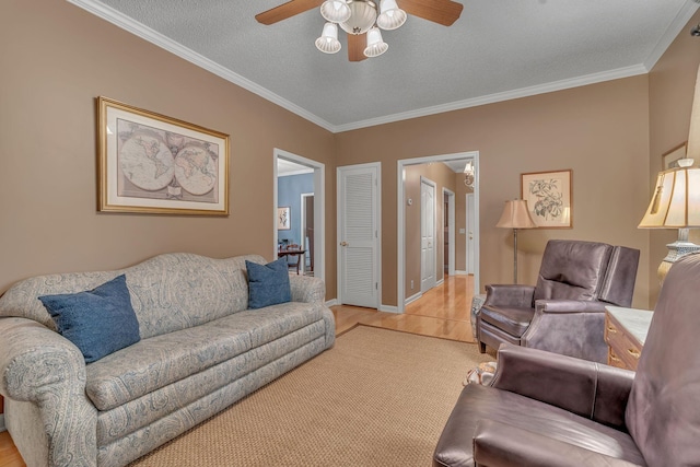 living room with ceiling fan, ornamental molding, a textured ceiling, and light hardwood / wood-style flooring