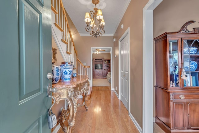 corridor with a notable chandelier, ornamental molding, a textured ceiling, and light hardwood / wood-style flooring