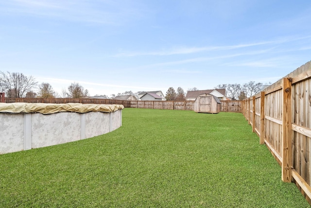 view of yard with a covered pool and a storage shed