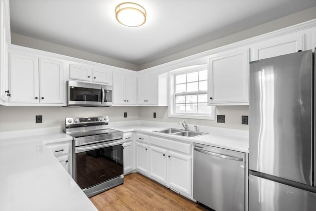 kitchen with white cabinetry, sink, light hardwood / wood-style floors, and appliances with stainless steel finishes