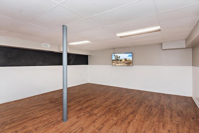 basement featuring a paneled ceiling and dark wood-type flooring