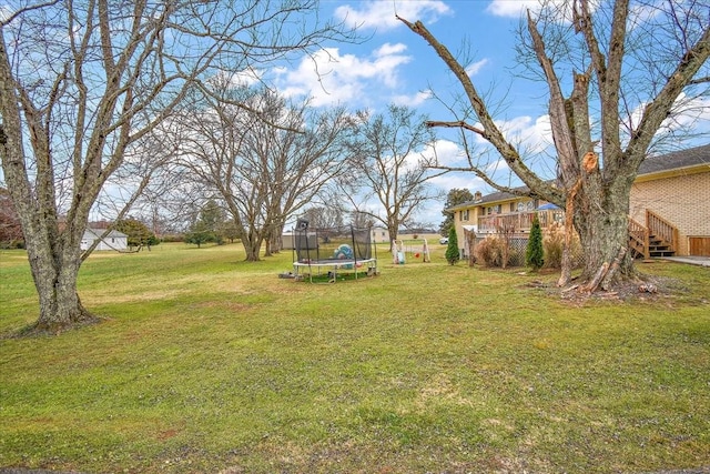 view of yard with a wooden deck and a trampoline