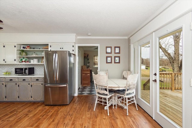 kitchen with light wood-type flooring, appliances with stainless steel finishes, backsplash, and gray cabinetry