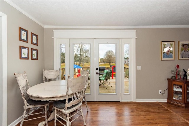 dining area with a textured ceiling, wood-type flooring, and ornamental molding