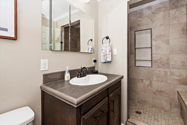 bathroom featuring tiled shower, vanity, toilet, and crown molding