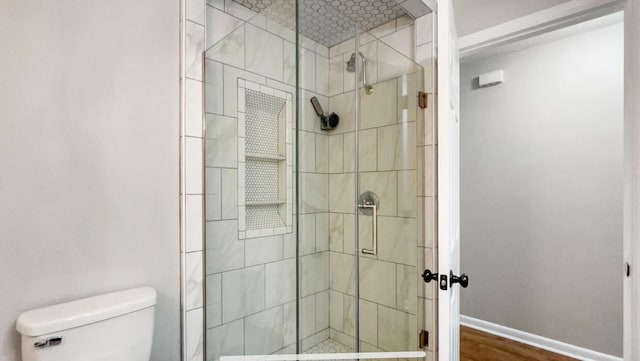 bathroom featuring toilet, wood-type flooring, and walk in shower