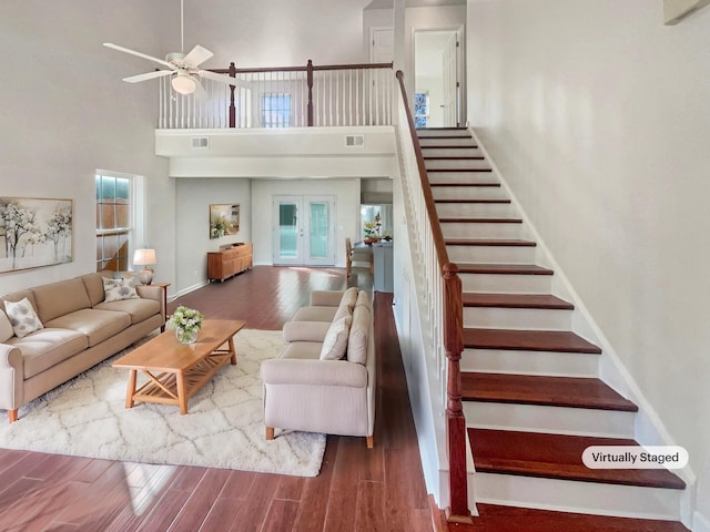 living room featuring ceiling fan, french doors, a towering ceiling, and wood-type flooring