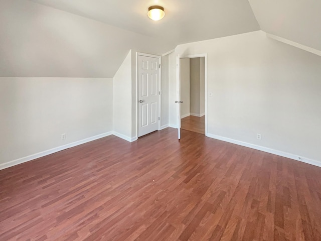 additional living space featuring dark wood-type flooring and vaulted ceiling