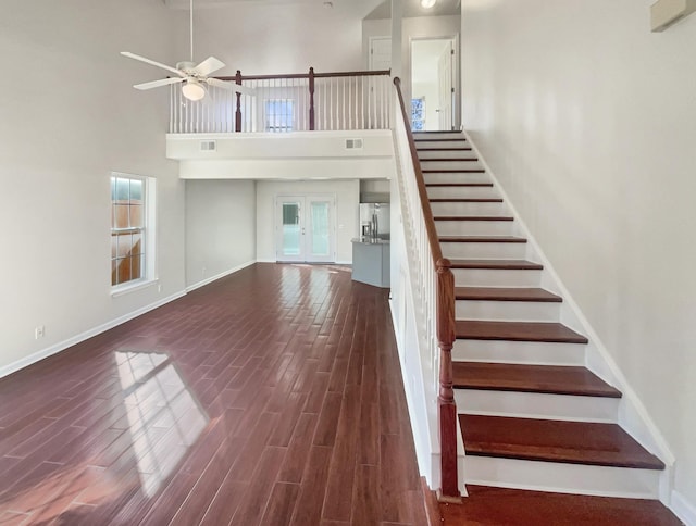 stairway featuring hardwood / wood-style floors, a towering ceiling, and ceiling fan