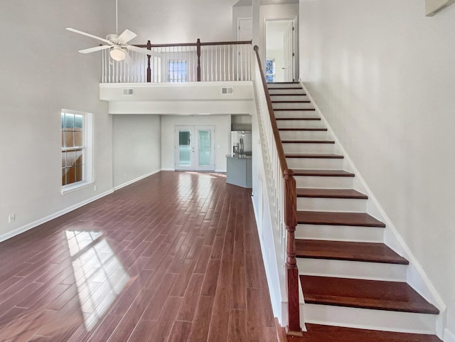 interior space featuring ceiling fan, a healthy amount of sunlight, wood-type flooring, and a towering ceiling