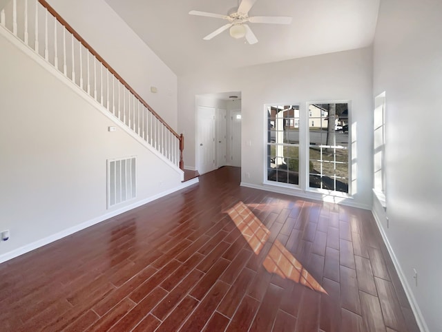 unfurnished living room featuring ceiling fan, dark hardwood / wood-style flooring, and a towering ceiling