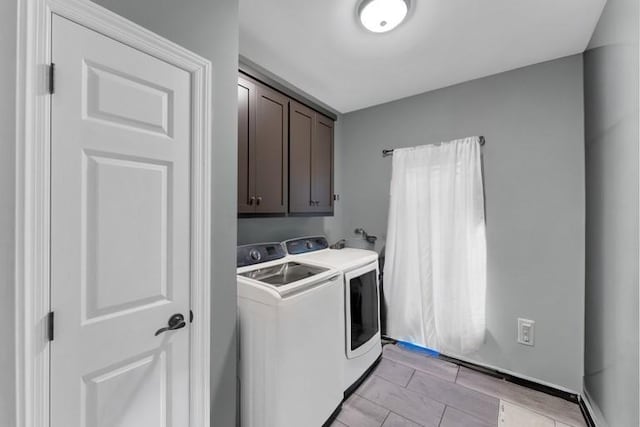 clothes washing area featuring cabinets and separate washer and dryer