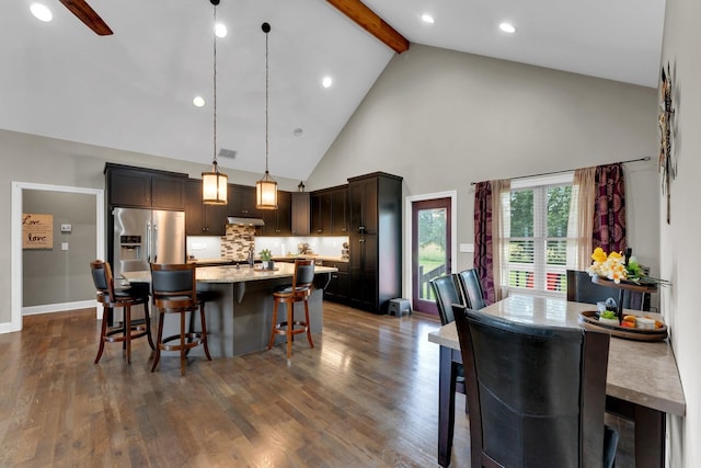 kitchen featuring pendant lighting, a center island with sink, high vaulted ceiling, and dark wood-type flooring