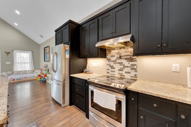 kitchen with lofted ceiling, backsplash, light hardwood / wood-style floors, light stone counters, and stainless steel appliances