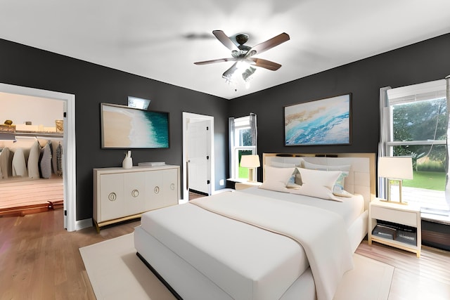 bedroom featuring hardwood / wood-style flooring, ceiling fan, a closet, and multiple windows