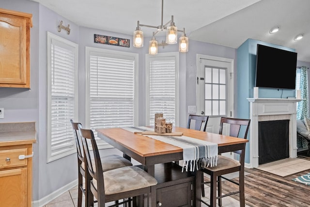 dining room featuring light wood-type flooring, a fireplace, and a chandelier