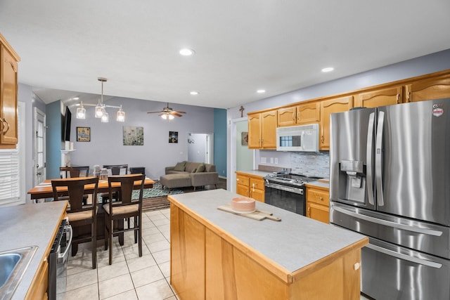 kitchen with pendant lighting, a center island, ceiling fan, light tile patterned floors, and appliances with stainless steel finishes