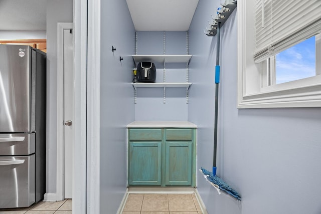 kitchen with light tile patterned flooring, green cabinets, and stainless steel refrigerator