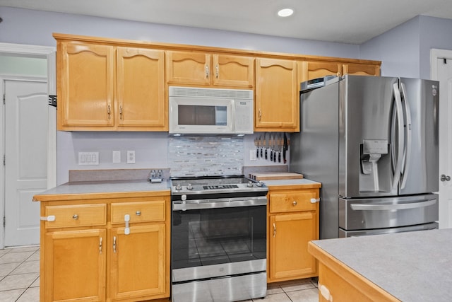 kitchen with decorative backsplash, light tile patterned floors, stainless steel appliances, and light brown cabinetry