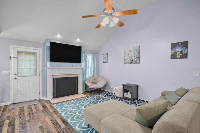 living room featuring high vaulted ceiling, ceiling fan, a tile fireplace, and light hardwood / wood-style flooring