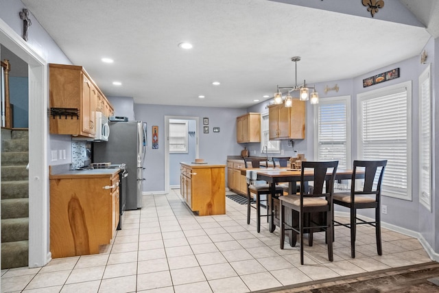 kitchen featuring a textured ceiling, light tile patterned flooring, hanging light fixtures, and black electric range