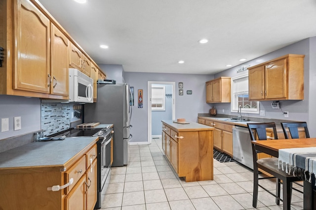 kitchen with decorative backsplash, appliances with stainless steel finishes, sink, light tile patterned floors, and a kitchen island