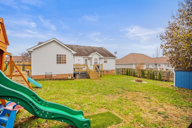 back of house featuring a yard, a playground, a fire pit, and a wooden deck