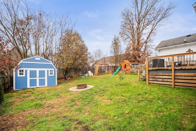 view of yard with a playground, a wooden deck, and a fire pit