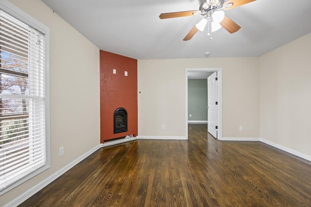 interior space featuring ceiling fan, a large fireplace, and dark hardwood / wood-style flooring