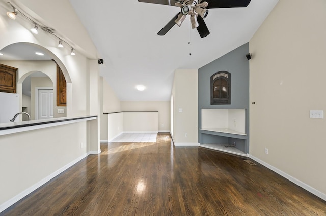 unfurnished living room with ceiling fan, rail lighting, lofted ceiling, and hardwood / wood-style flooring