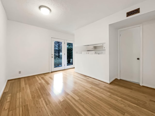 unfurnished room featuring light wood-type flooring and a textured ceiling