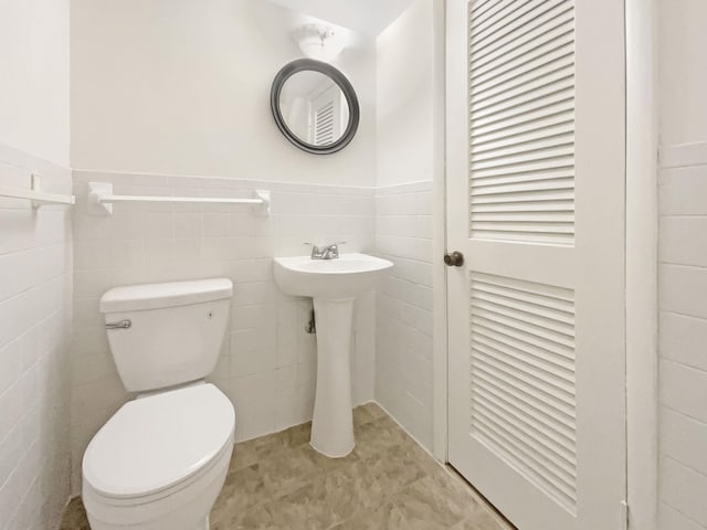 bathroom featuring toilet and tile walls