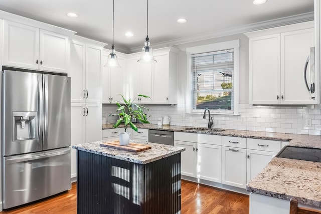 kitchen featuring white cabinetry, a center island, sink, stainless steel appliances, and decorative light fixtures