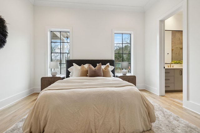 bedroom with sink, ensuite bath, light hardwood / wood-style floors, and crown molding