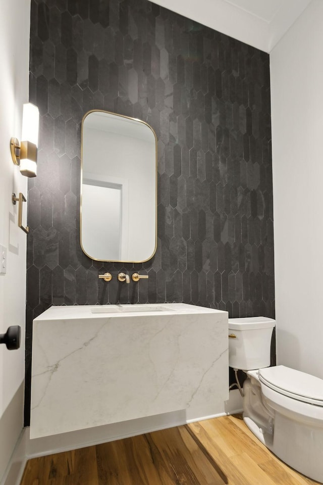 bathroom with toilet, hardwood / wood-style flooring, tile walls, and decorative backsplash