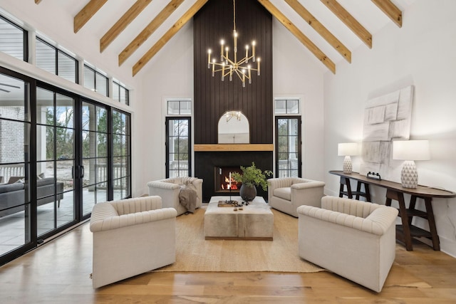 living room featuring a chandelier, light hardwood / wood-style floors, beamed ceiling, high vaulted ceiling, and a fireplace