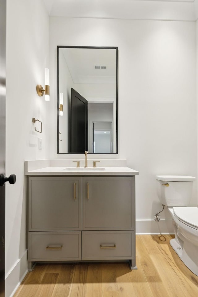 bathroom featuring toilet, wood-type flooring, and vanity