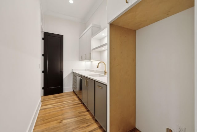 kitchen with dishwasher, light hardwood / wood-style floors, white cabinetry, ornamental molding, and sink