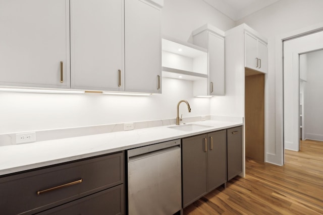 kitchen with light stone counters, stainless steel dishwasher, dark hardwood / wood-style floors, white cabinetry, and sink